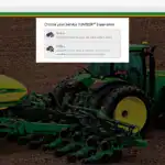 Green and yellow John Deere tractor with seed planter attachment on a farm field, demonstrating agricultural machinery for planting crops.