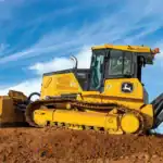 Yellow John Deere bulldozer at construction site on dirt hill, large construction equipment for earthmoving.